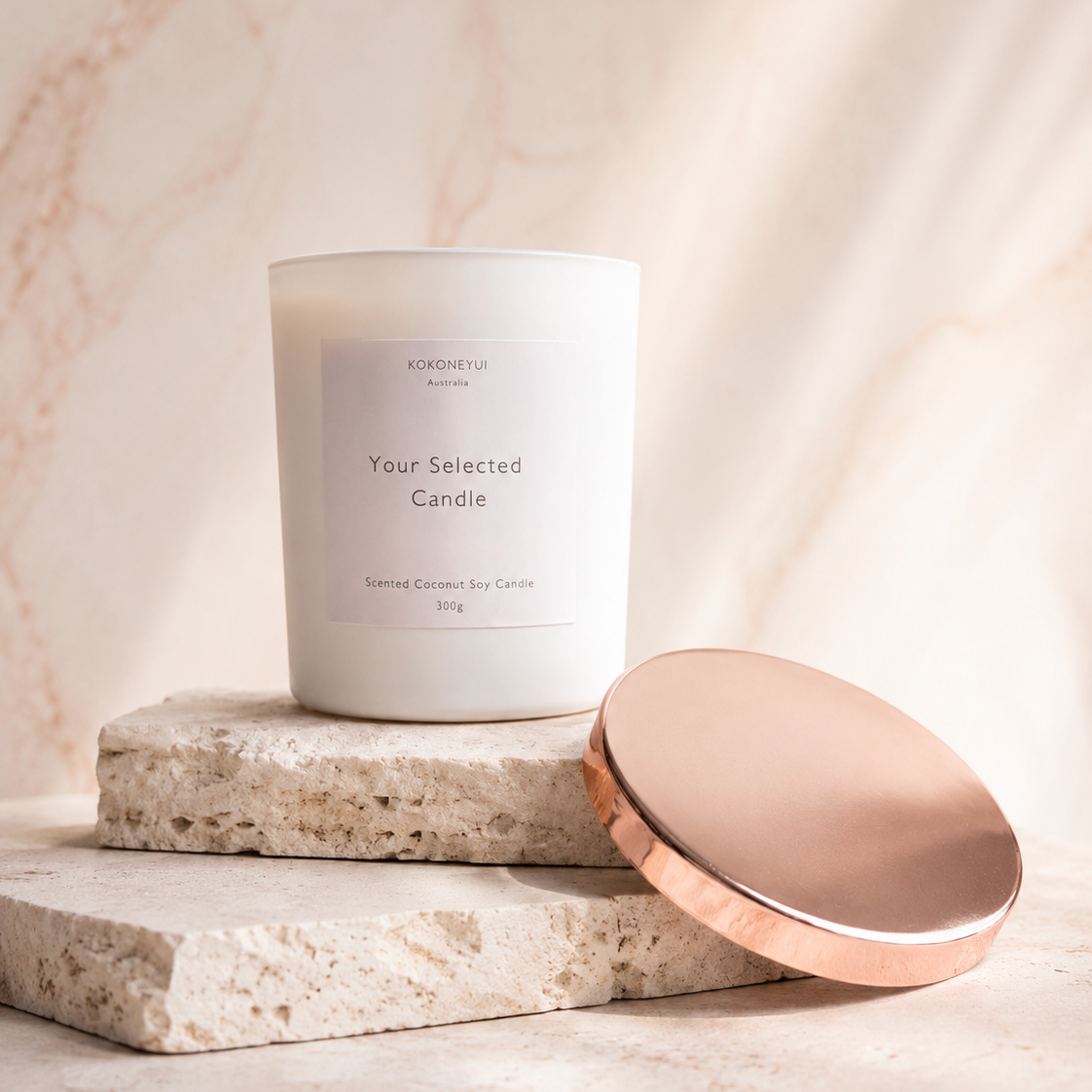 Candle with a white label on a stone surface with a soft pink background
