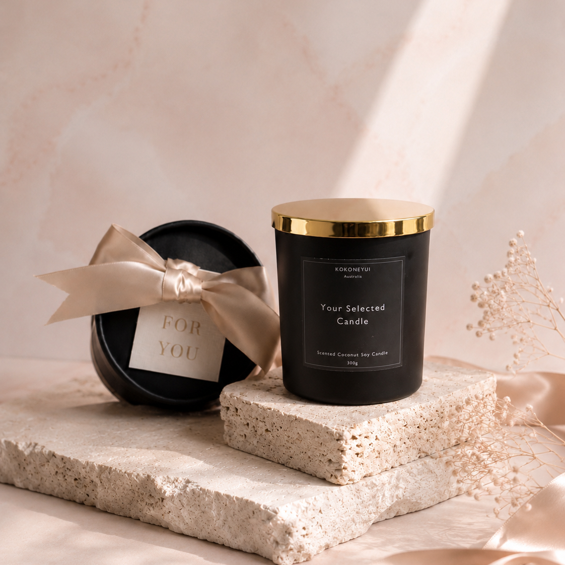 Black candle with gold lid on a textured surface with a soft pink background