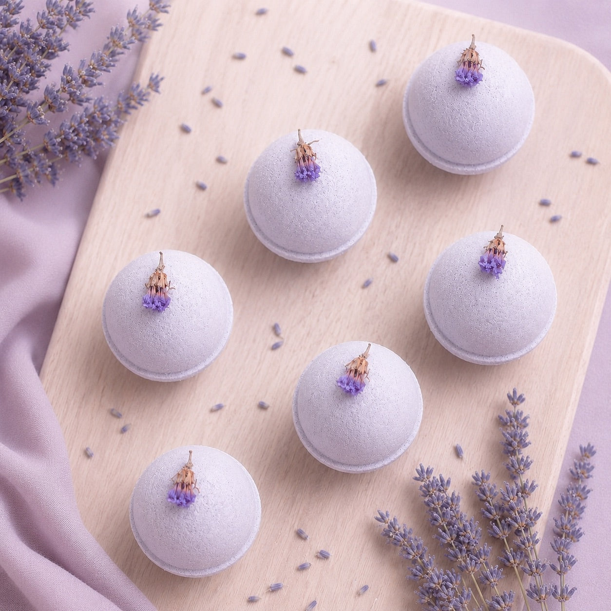 Bath bombs with lavender flowers on a wooden board with scattered lavender petals.