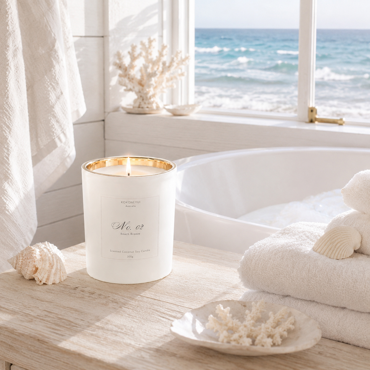 Candle in a white label with gold rim on a windowsill with a view of the ocean.