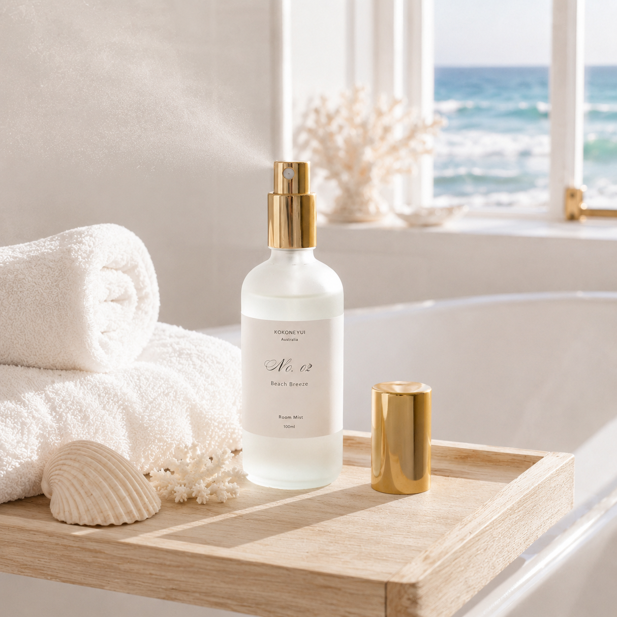 Room mist bottle with gold cap on a wooden tray by a bathtub with ocean view