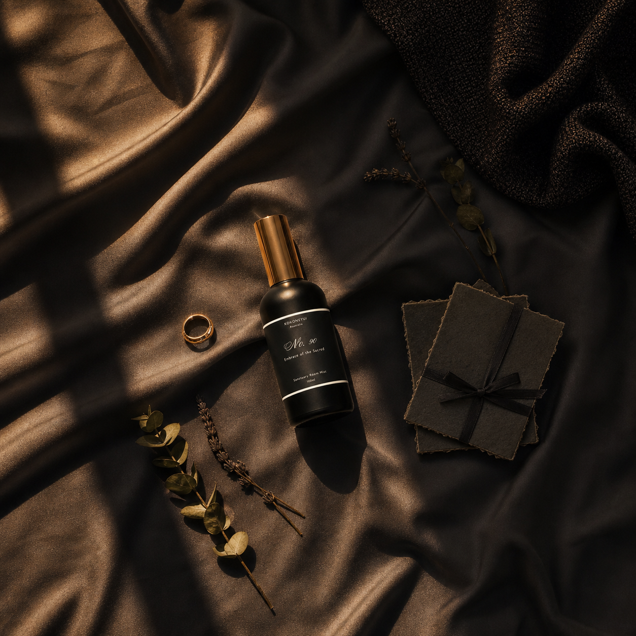 Room Mist bottle with gold cap on dark fabric with decorative elements