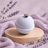 Bath bomb with lavender flowers on a wooden stand against a soft pink background