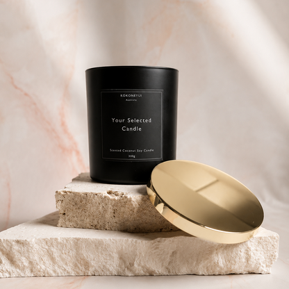 Black candle with a gold lid on a marble surface