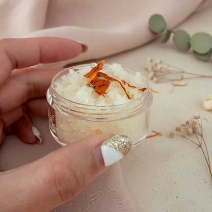 Hand holding a small jar of  Scrub with orange calendula