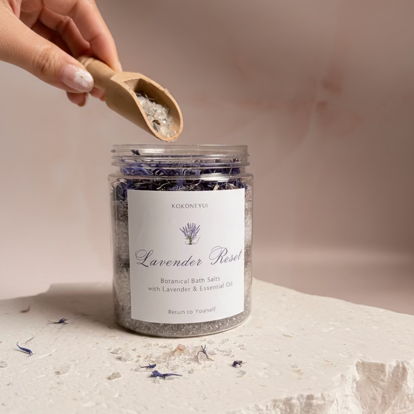 Jar of lavender bath salts with a hand holding a scoop on a light background