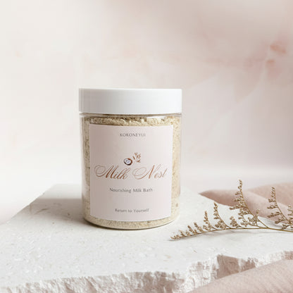 Jar of Milk Nest Bath Milk on a textured white surface with a light gray background