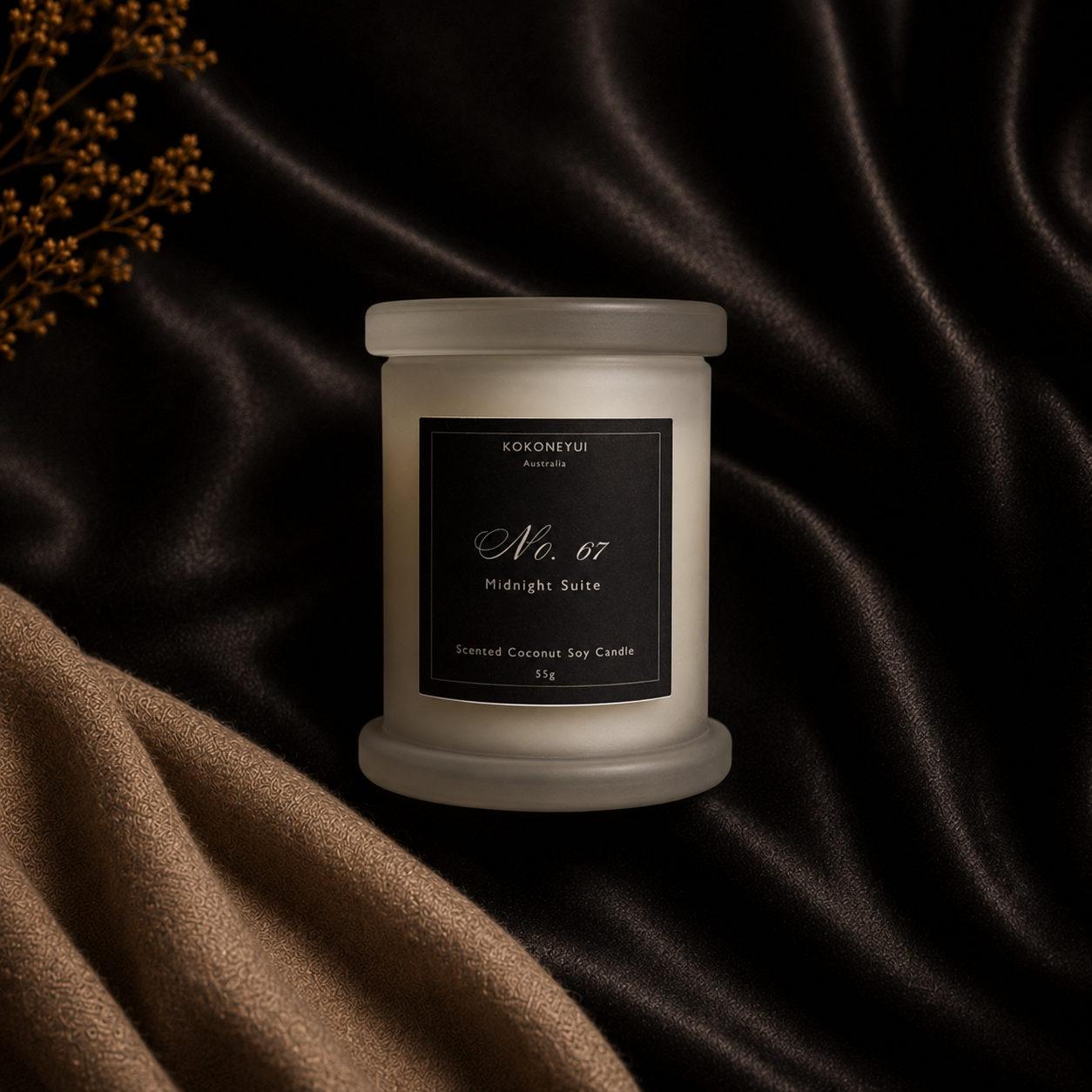 A frosted glass jar candle with a black label &
