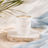 White No.02 candle with gold rim on a stone platform against a soft, blurred background