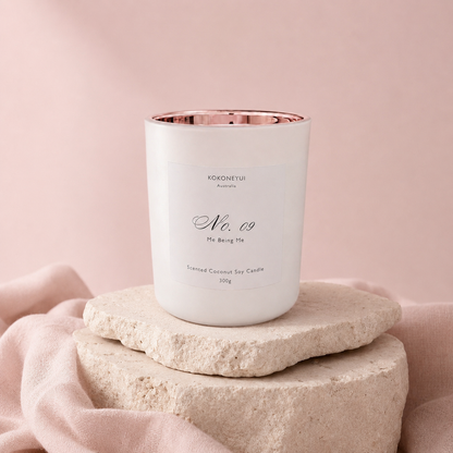 Candle with a rose gold interior on a stone platform against a pink background