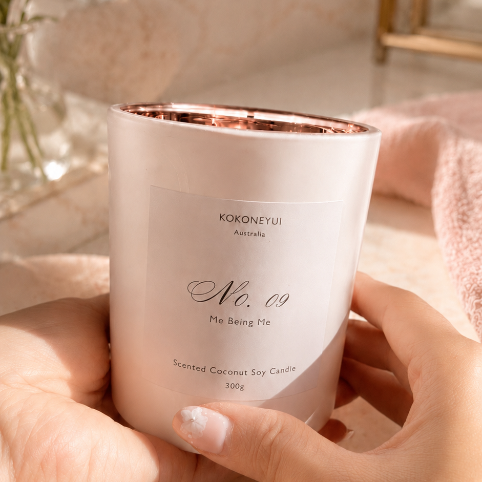 Hand holding a white candle with rose gold interior, brand &