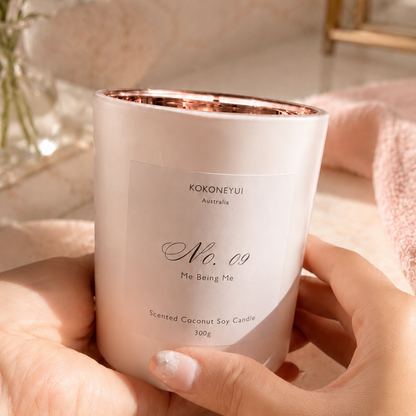 Hand holding a white candle with rose gold interior, brand &