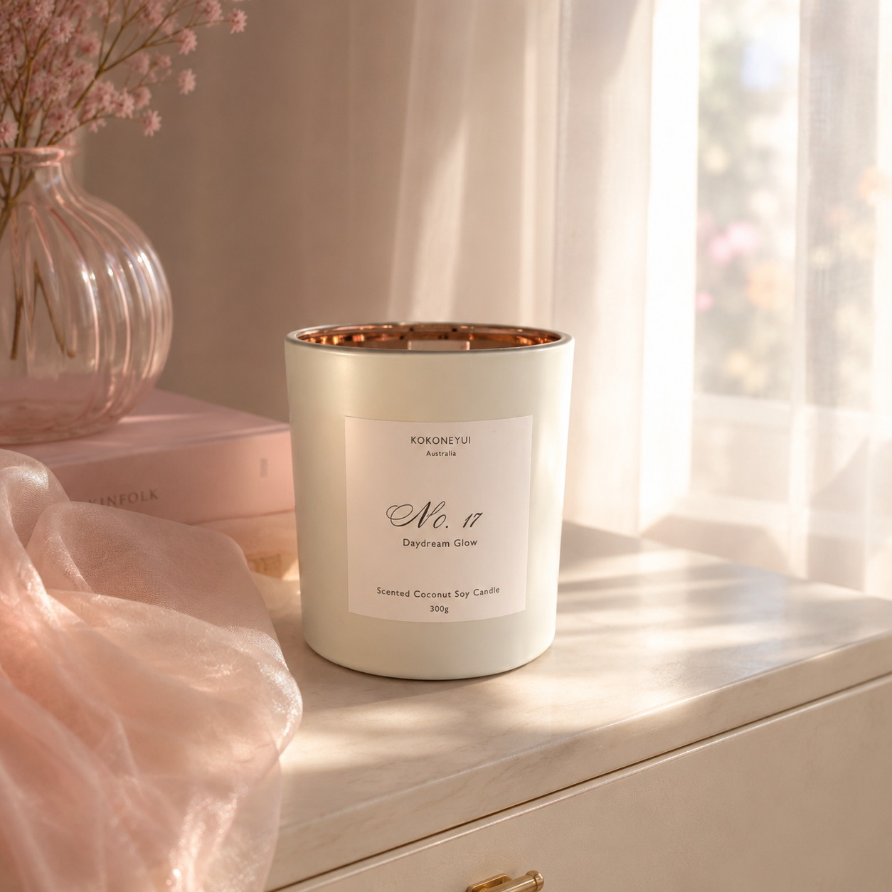 Candle with a label on a surface with soft lighting and decor elements.