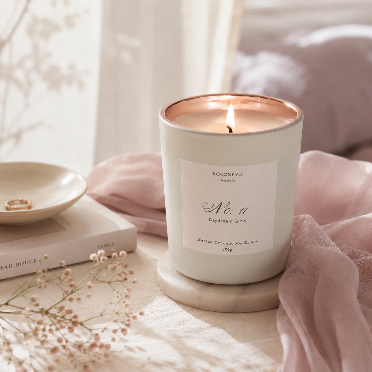 Lit candle in a white container with a label on a soft surface