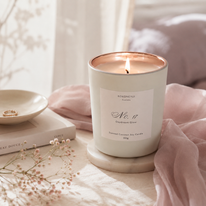 Lit candle in a white container with a label on a soft surface