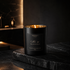 Black candle with gold interior on a dark surface, brand &