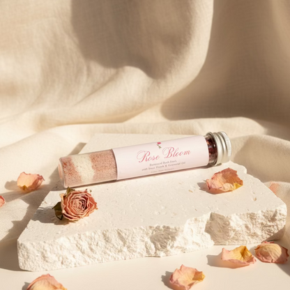 Rose Bloom product tube on a textured white surface with a light gray background