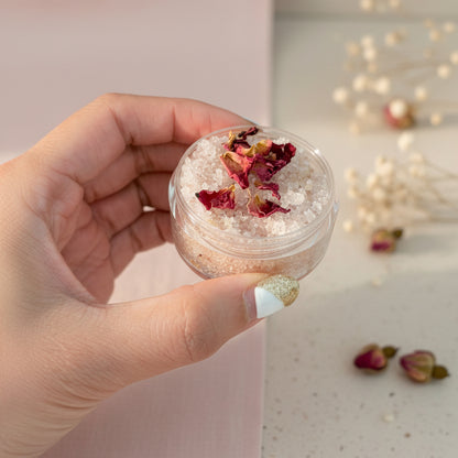 Hand holding a small scrub container with a decorative item on a beige background