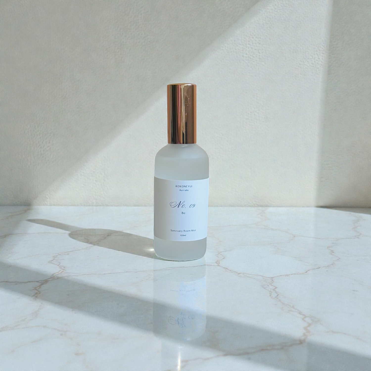frosted spray bottle with rose gold cap on a marble surface