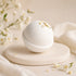 White bath bomb with Jasmine petals on a beige stand with flowers in the background