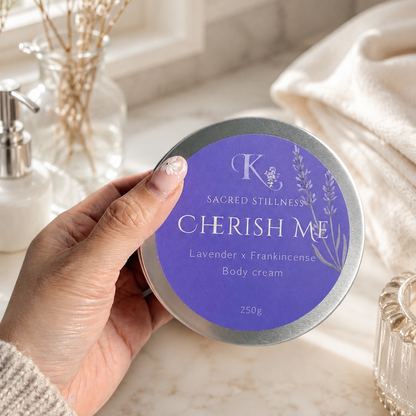 A woman hand holding a body cream tin labelled Cherish me 