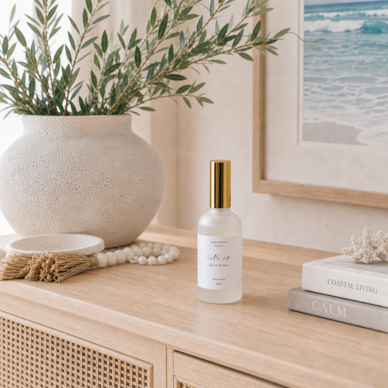 White room mist bottle with gold cap on a wooden surface with decorative items