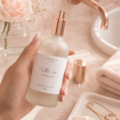 Hand holding a bottle of Kokoneyui product on a bathroom counter with roses and a faucet in the background.