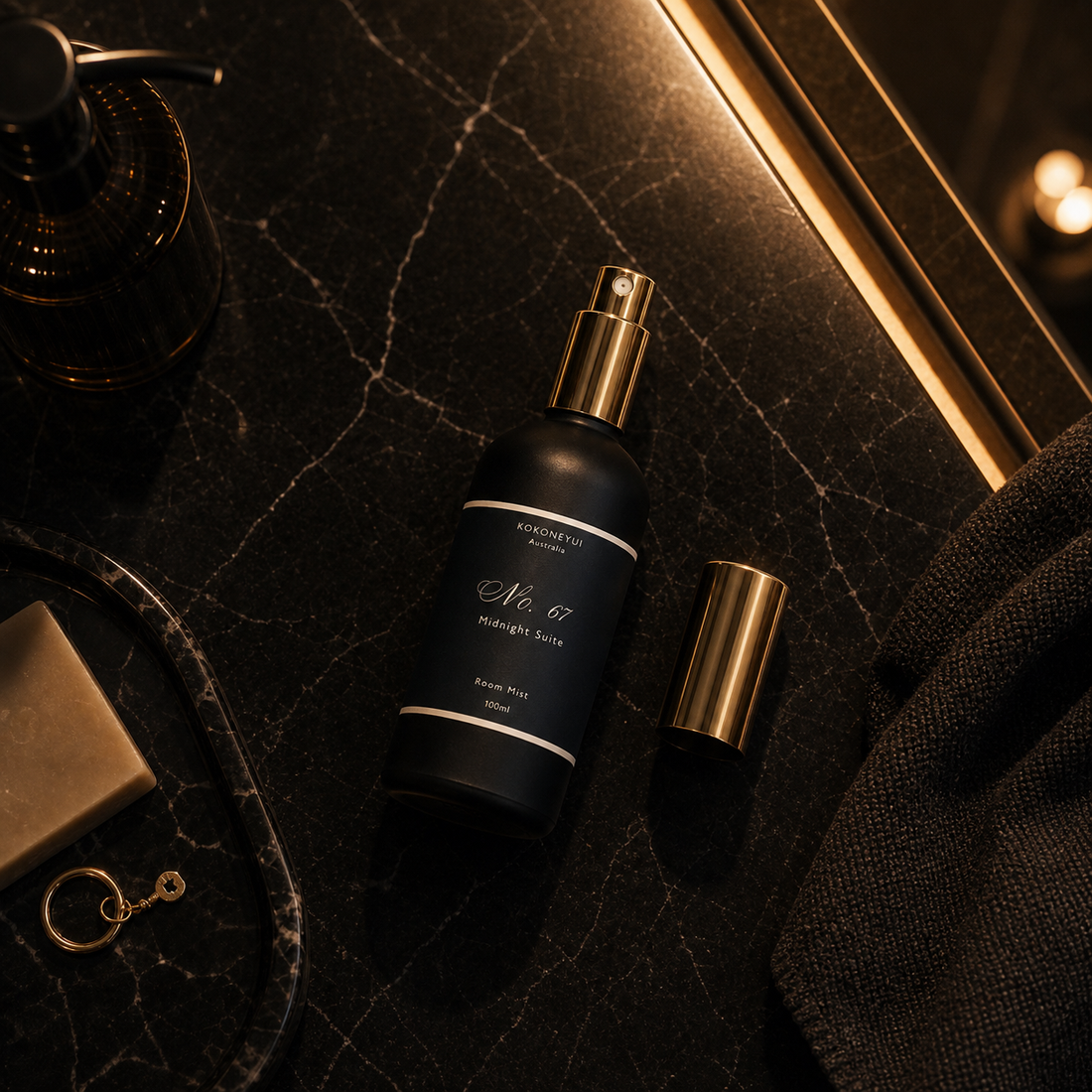 Black spray bottle with gold cap on a dark textured surface