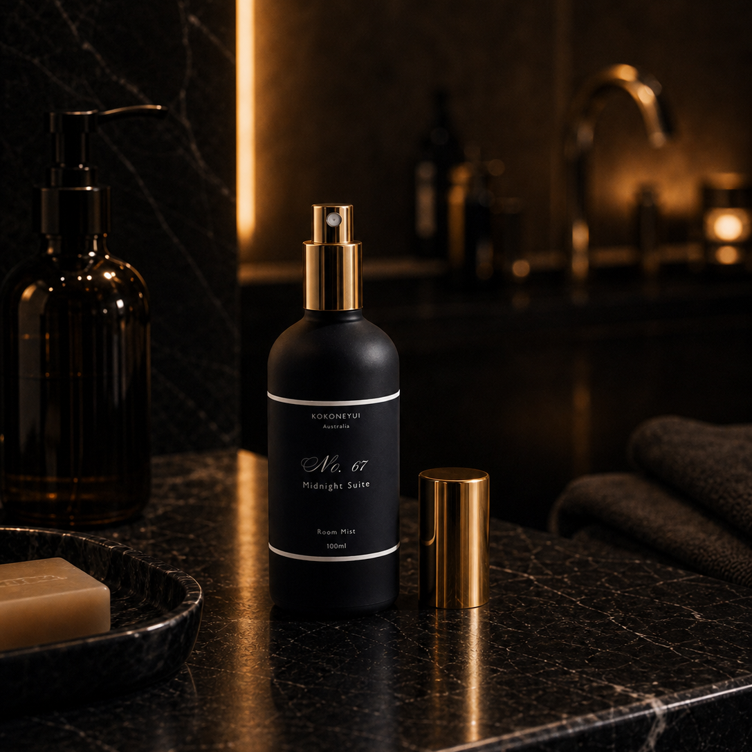 Black spray bottle with gold cap on a dark marble surface in a bathroom setting