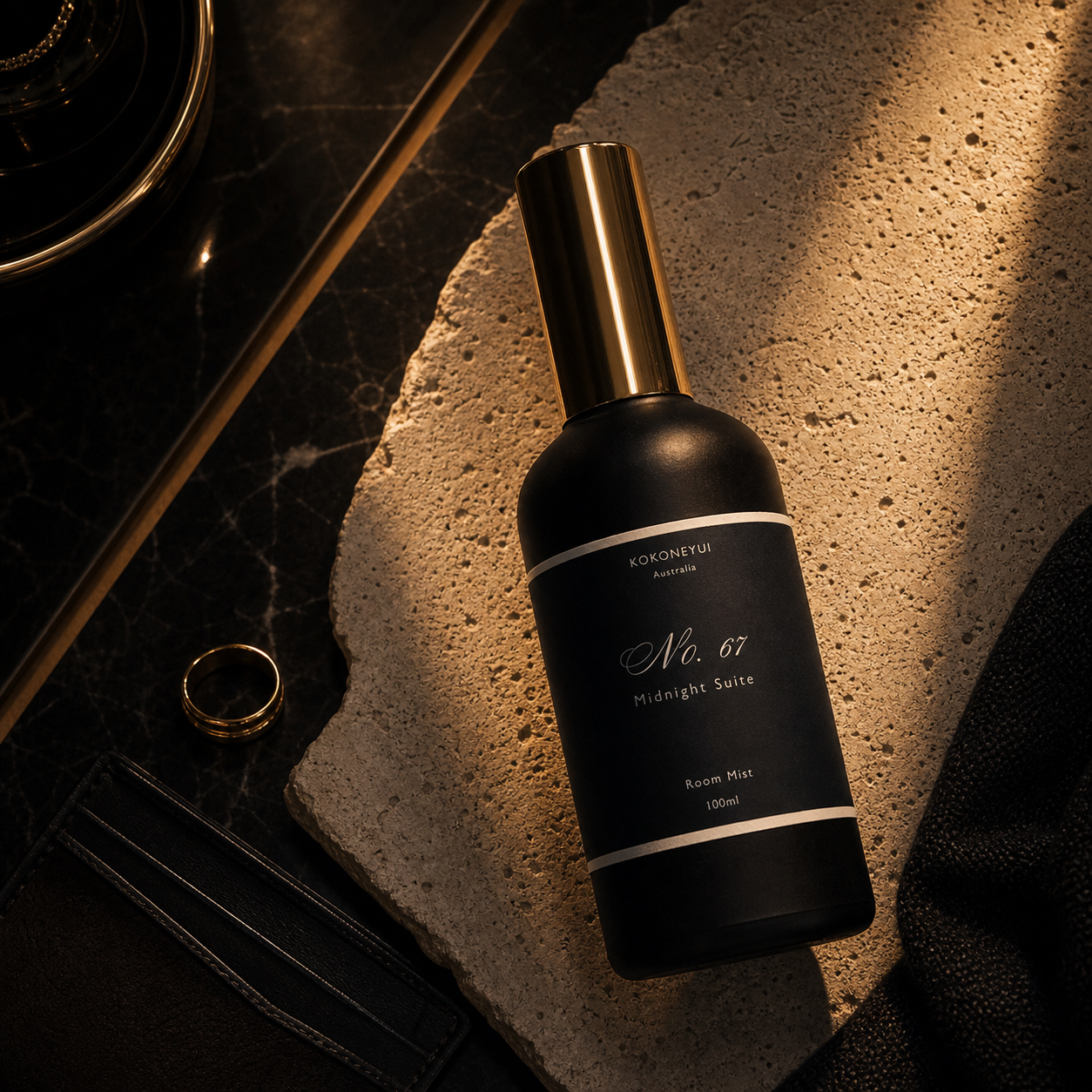 Black room mist bottle with gold cap on a textured surface