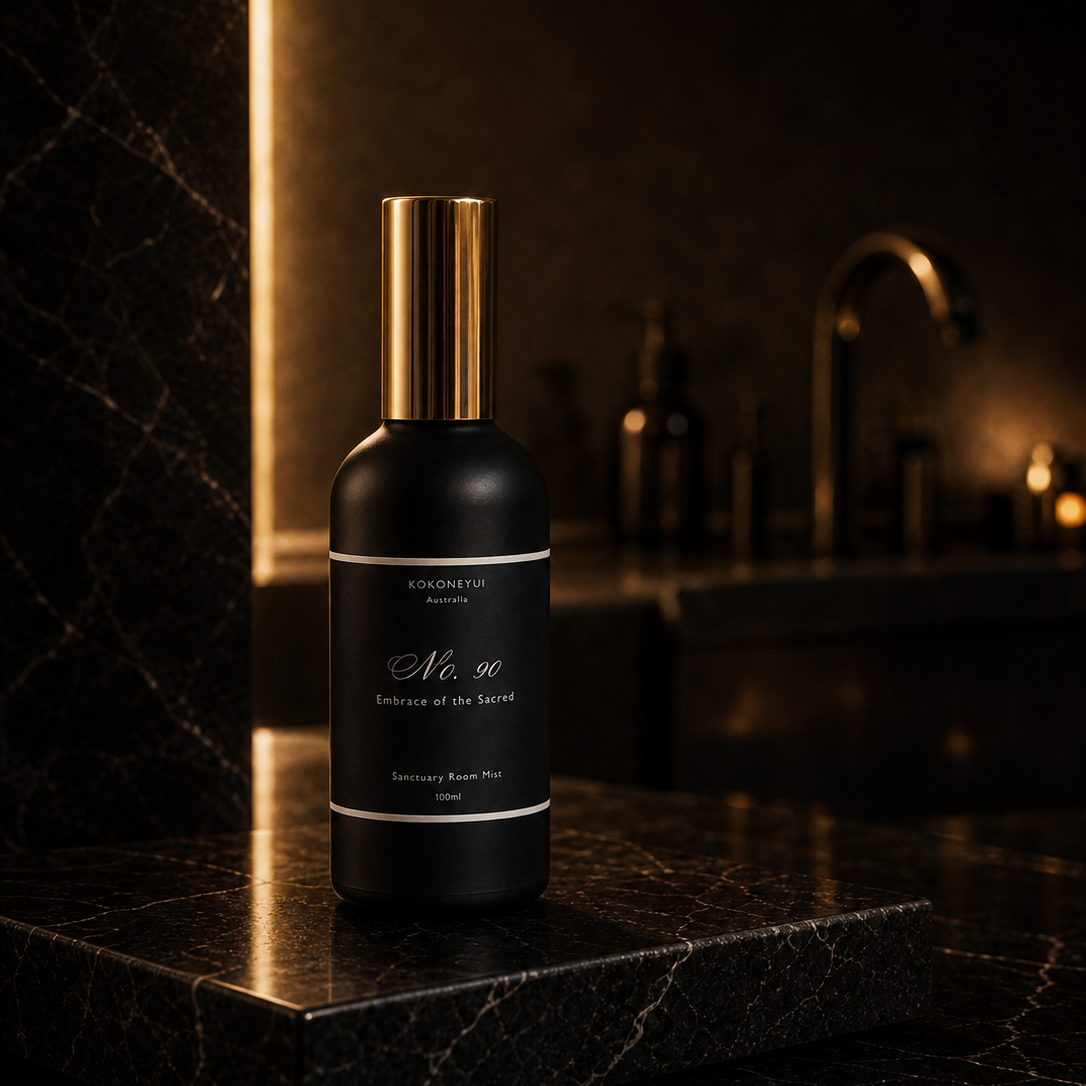 Black spray bottle with gold cap on a dark marble surface