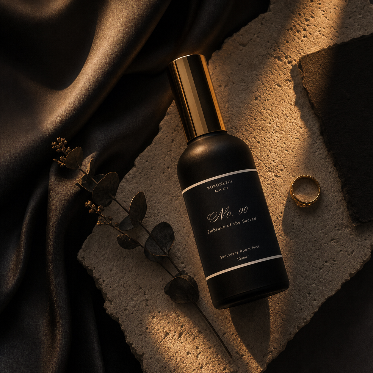 Black Mist bottle with gold cap on a textured surface with a ring and leaves.