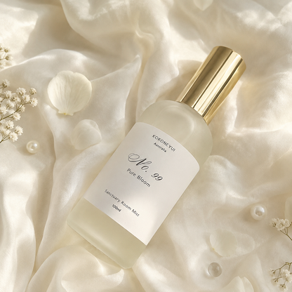 Bottle of KOKONEYUI No. 99 Pure Bloom room mist on a soft, light fabric background with small flowers.